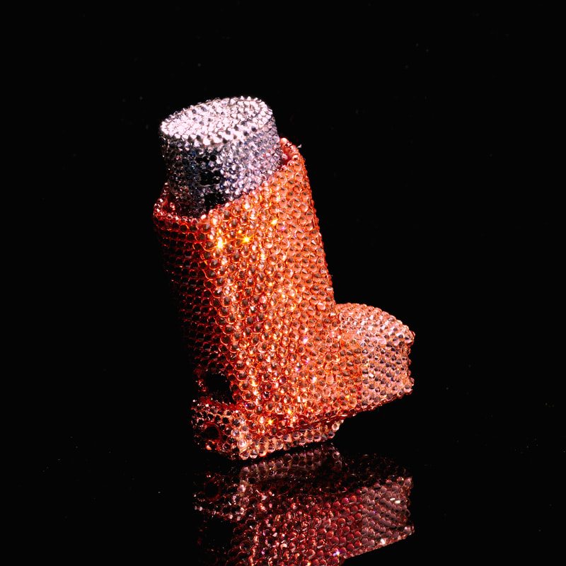 AN L-shaped inhaler covered in orange and lilac rhinestones.