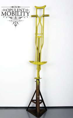A bright yellow crutch attached to a bright yellow pogo stick, mounted to a triangular black steel frame.