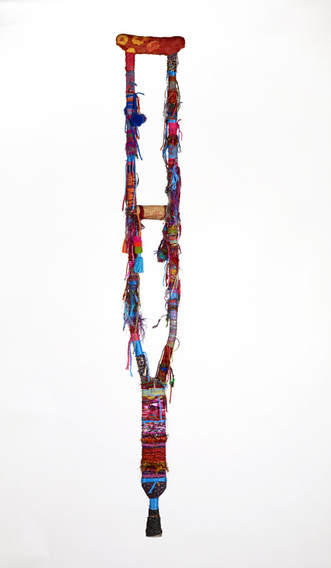 Crutch wrapped with brightly colored yarn, fabric, and tassels.
