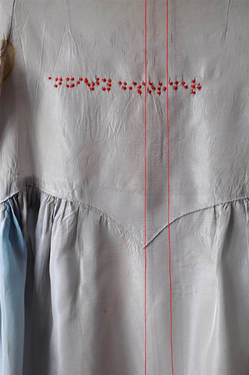 Detail of a grey dress with the Braille characters for 