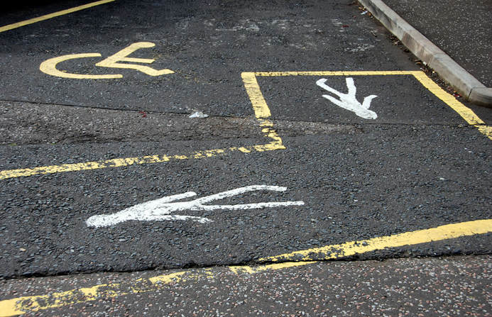 A photo of a confusing wheelchair accessible parking space with two walking figures painted on the side.
