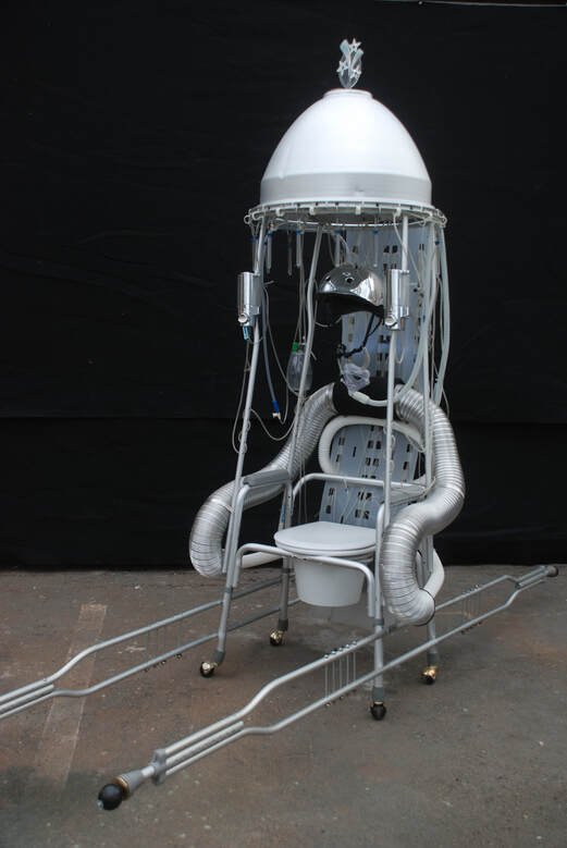 Futuristic silver and white walker with a hood,  toilet seat, metal helmet and tubing, and crutch handles.