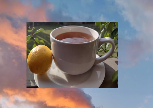 A white cup of tea on a white saucer with a lemon on the left of the cup. In the background are green jasmine leaves, and the whole picture floats on top of a picture of a sky at sunset with pink and orange clouds.