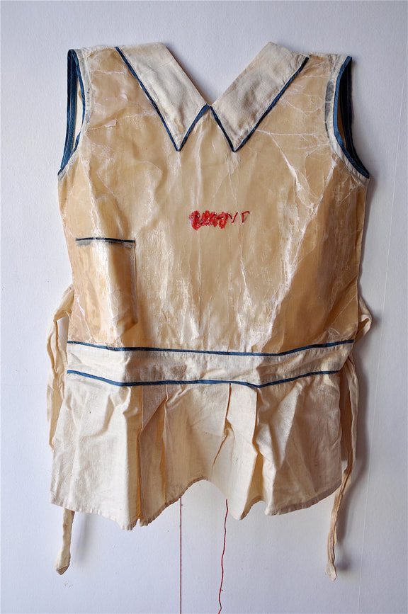 Photograph of a waxed children's apron with the Braille characters for 