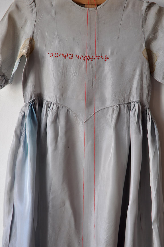 Picture of a grey dress with the Braille characters for 