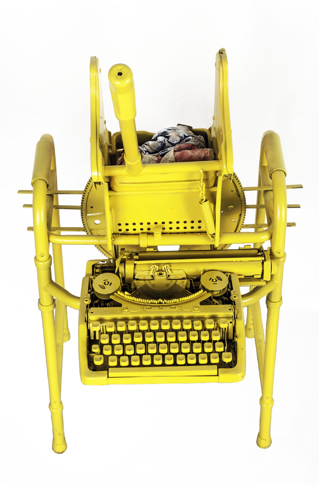 Tope view of a bright yellow walker with attached typewriter and mop wringer. In the mop wringer is a crumpled American flag.